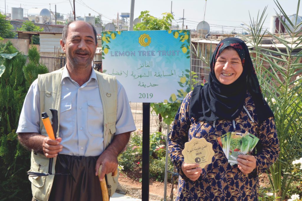 Muhammed Hssen and Zainab Abdullah holding their Garden of the Month plaque and seed packet prize